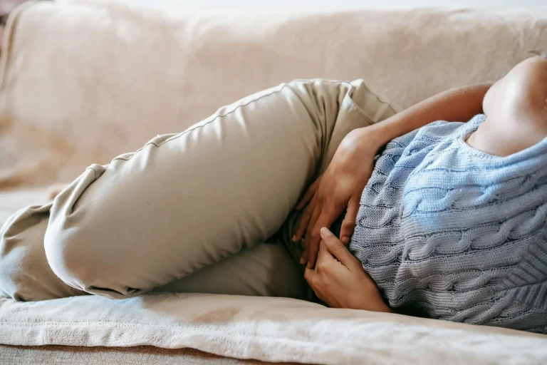 En la foto aparece a un mujer en un sofá, con las piernas recogidas y las manos en la zona del vientre