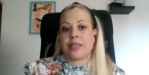 En la imagen aparece miriam sentada en una silla negra, va con una camiseta con flores de colores