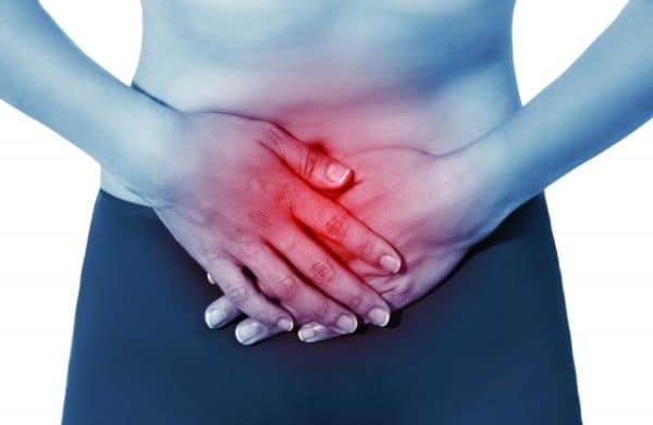 Dolor Pélvico, mujer con las manos en la zona del ombligo mostrando una zona de dolor en color rojo